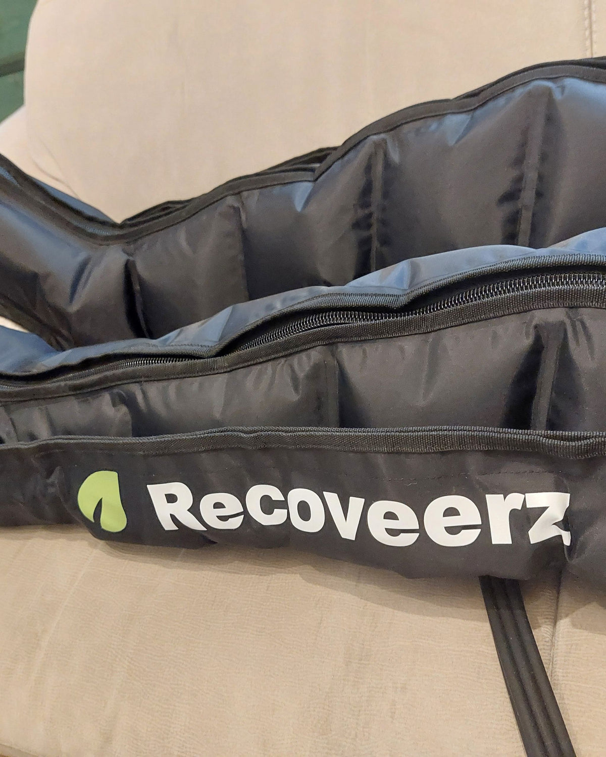 Bottes de pressothérapie Recoveerz 6 chambres posées sur un canapé, vendues sans boîtier