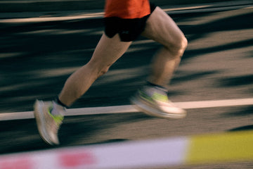 Jambes d'un coureur en pleine foulée sur une piste d'athlétisme